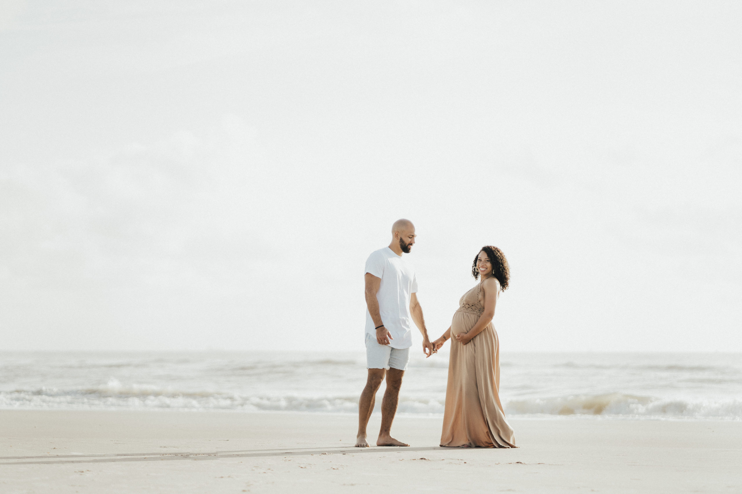 Candid moment of expecting parent walking on Jacksonville Beach