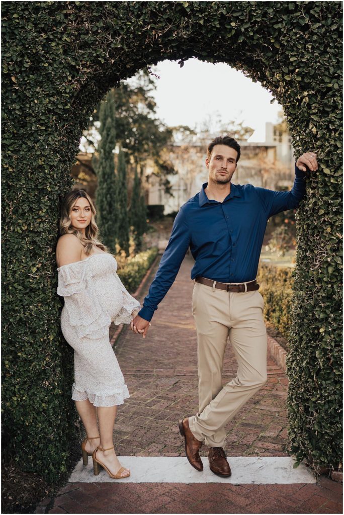 Fierce couple posing in the arch way of a garden for maternity session