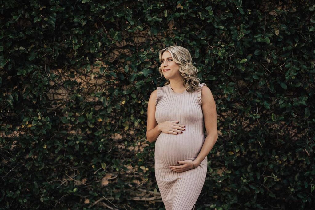 boho maternity photos in front of plant wall of ivy