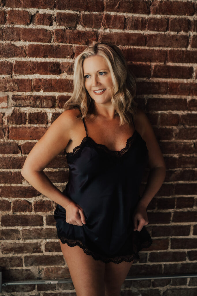 Woman posing against brick wall.