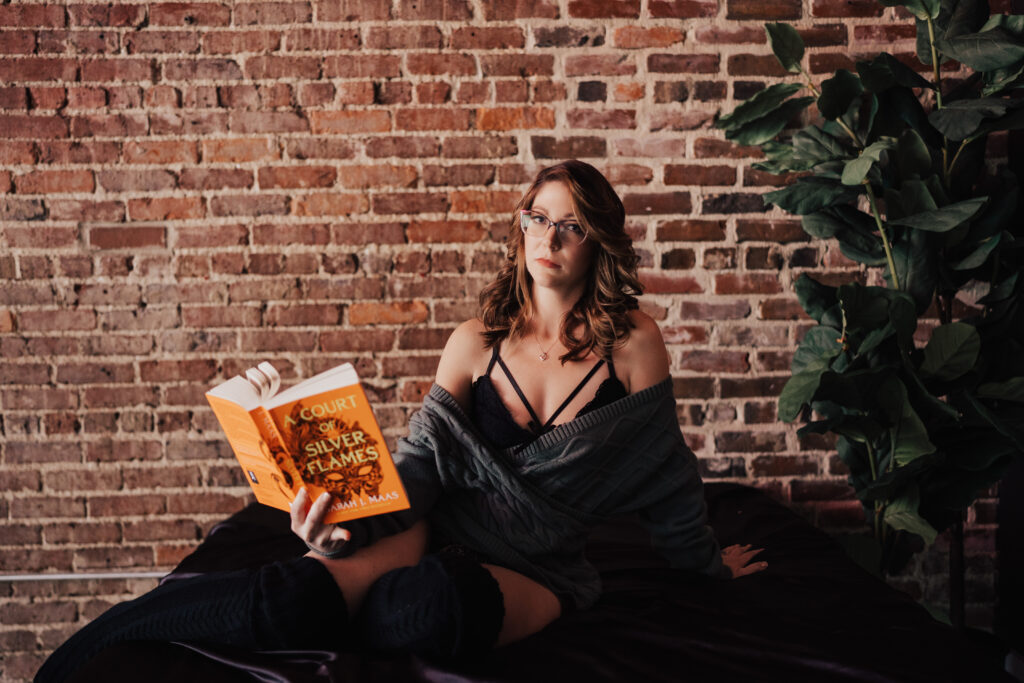 Woman posing on bed with a book in a unique boudoir photoshoot
