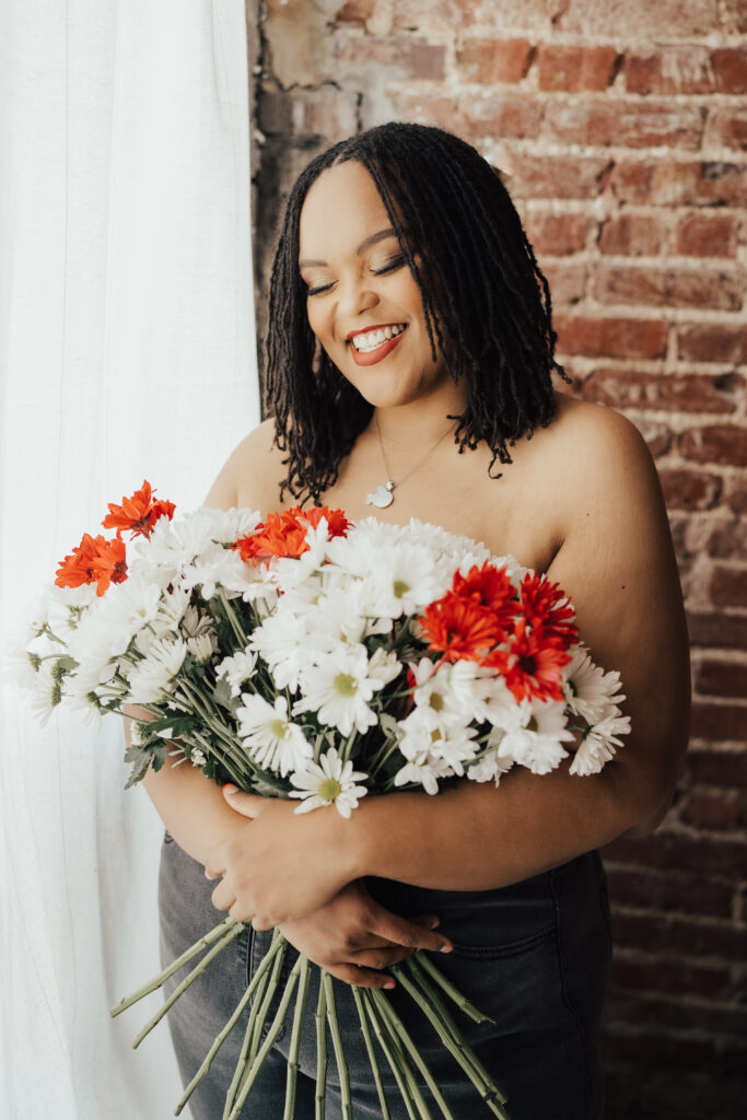 woman posing in boudoir photoshoot with flowers over chest for privacy